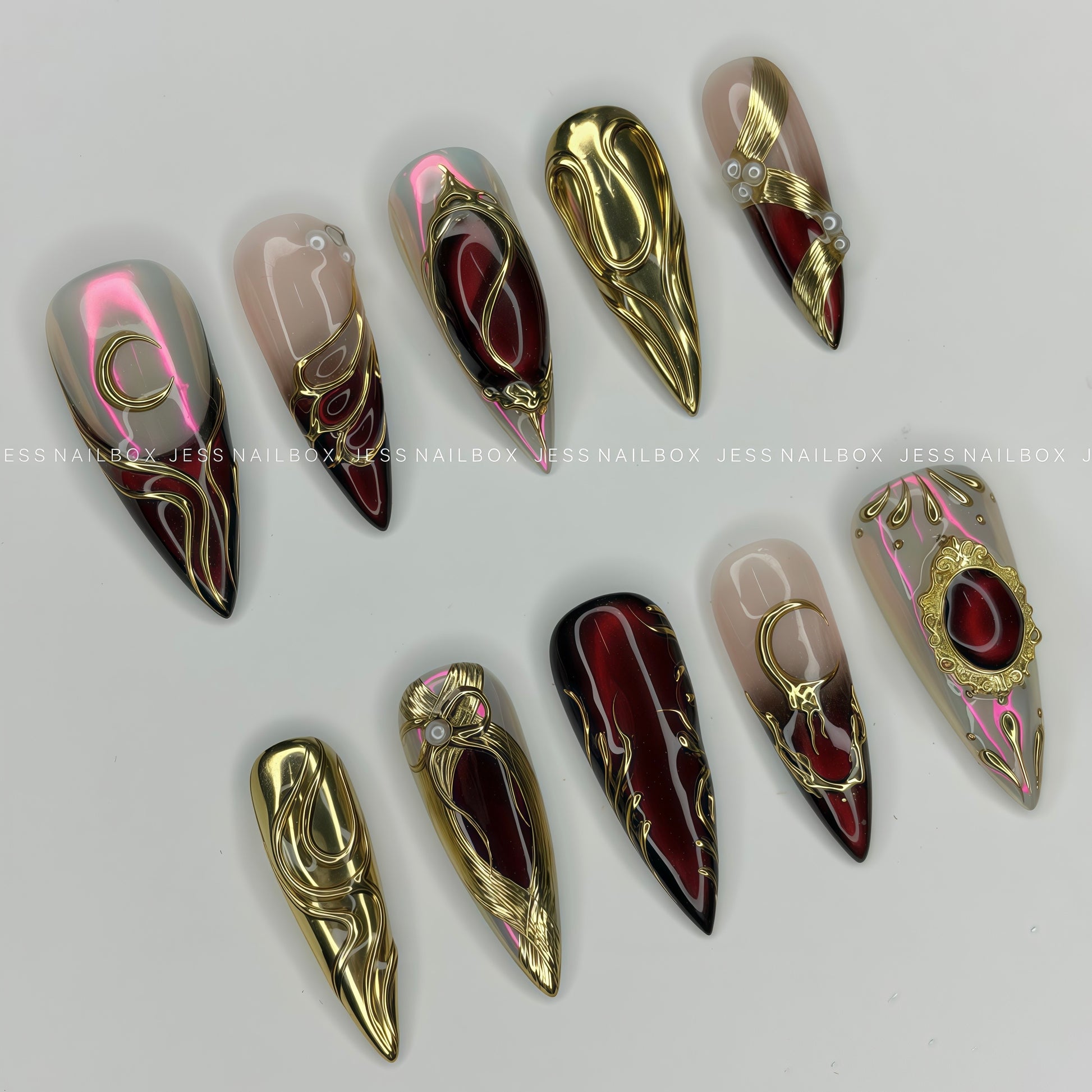 Decorative false nails with gold and red designs on a white background