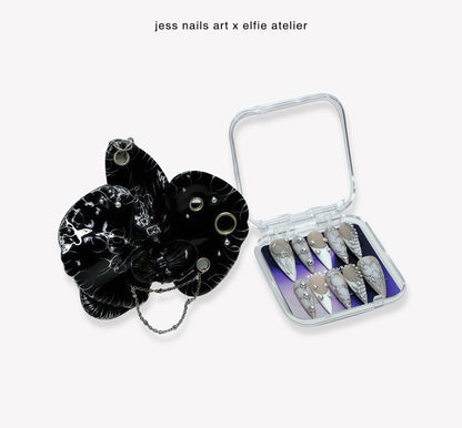 Noiré Duo - Handcrafted Onyx Black Orchid Charm Displayed Beside Nude System Press-On Nails in Clear Packaging Box