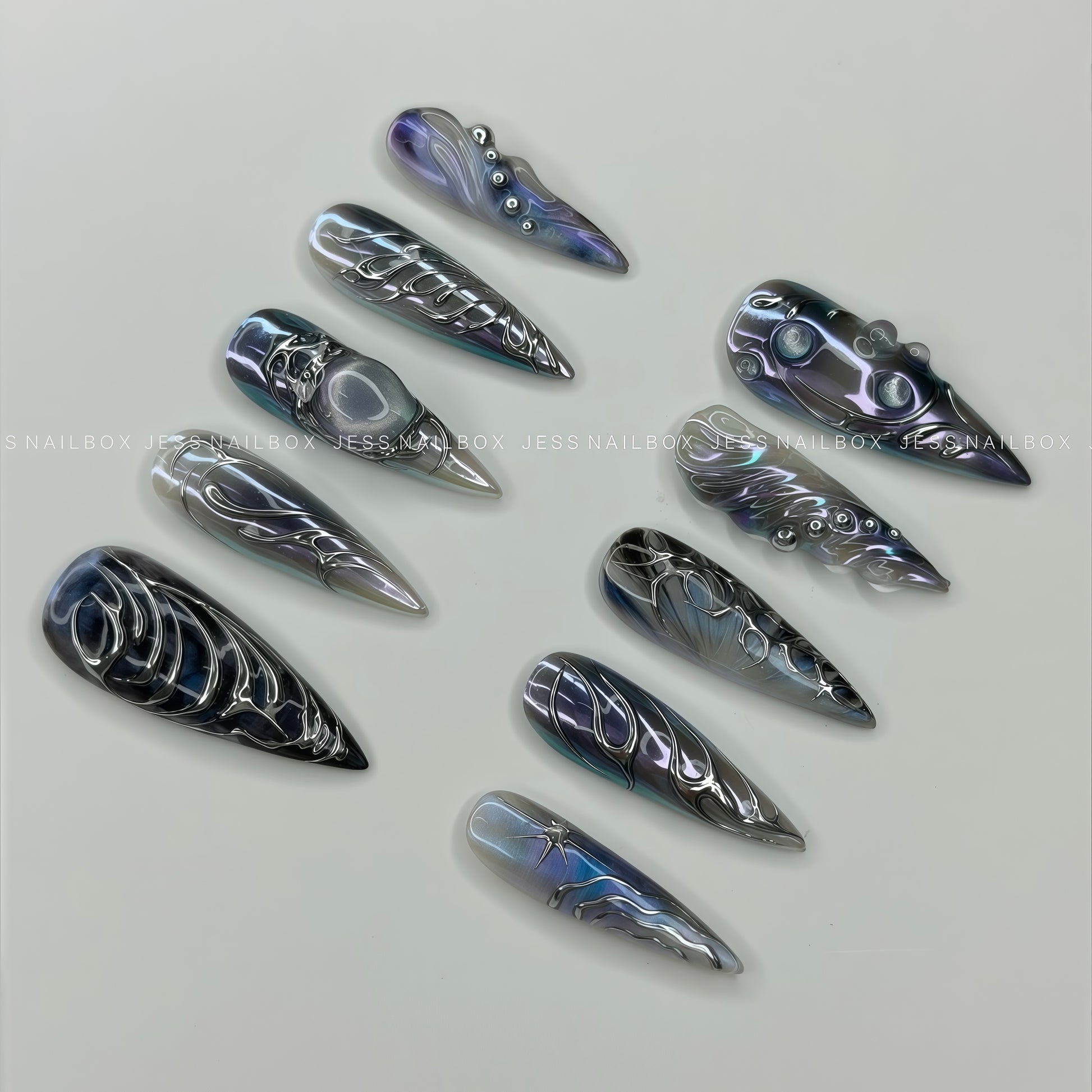 Close-up of Silver Nebula press-on nails showcasing the reflective chrome water droplets, intricate metallic linework, and galactic color shifts from a diagonal perspective.